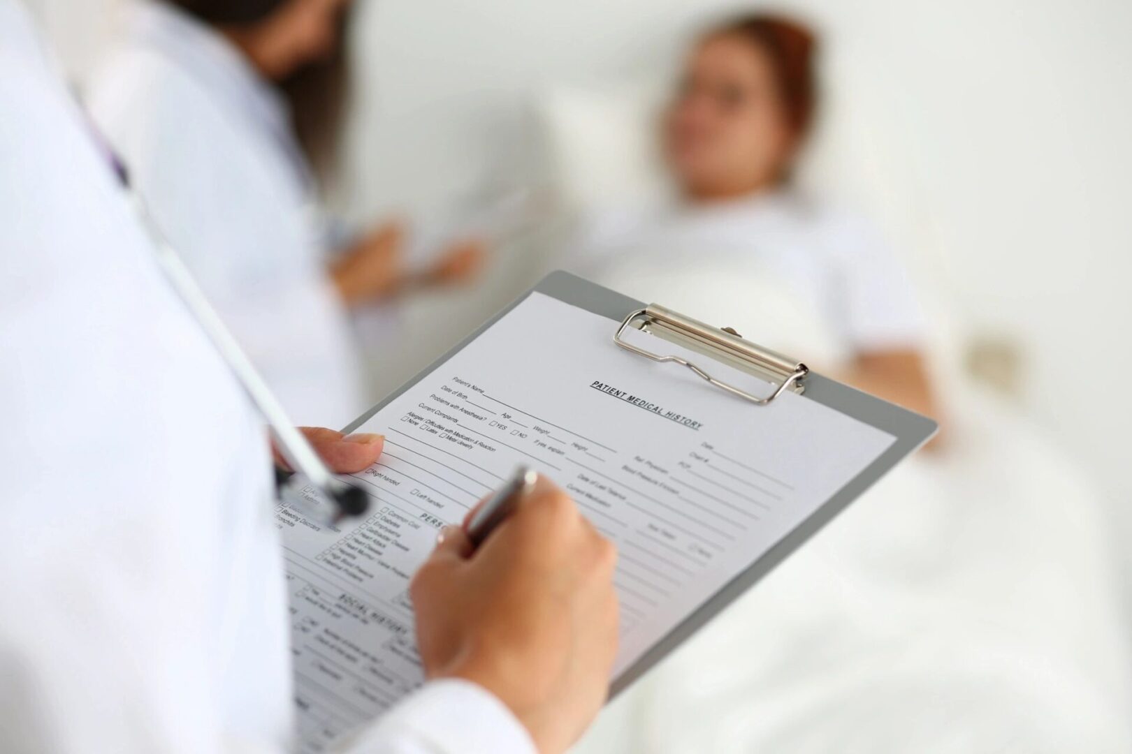 A doctor is holding a clipboard and writing on it.